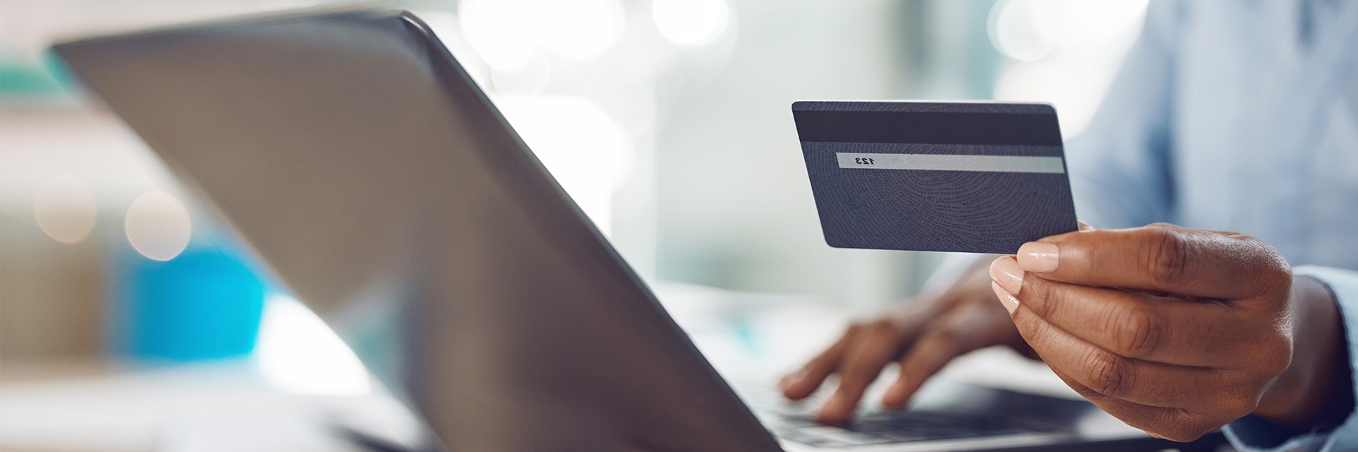 A person holding a credit card while on a laptop